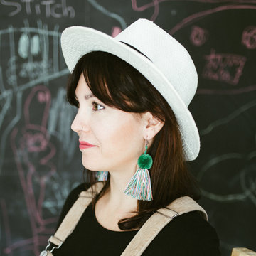 Side view of attractive trendy young brunette with green handmade earrings of threads