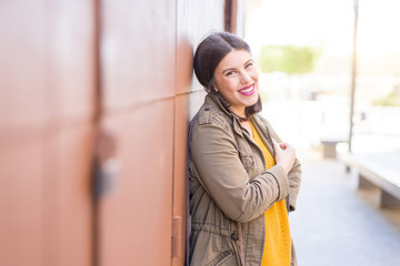 Fototapeta premium Beautiful young woman smiling confident and cheerful leaning on the wall, walking on the street of the city on a sunny day