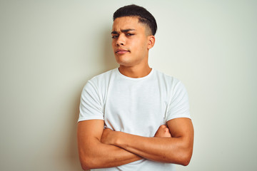 Young brazilian man wearing t-shirt standing over isolated white background skeptic and nervous,...