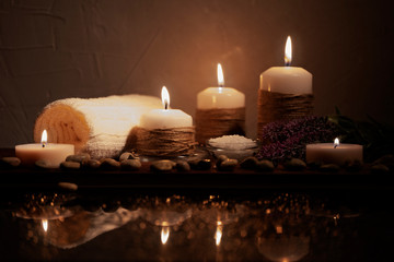 Spa concept in low key with beautiful bokeh. Pebbles, salt, flower and towel on dark wooden background.