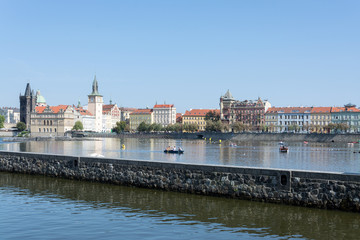 Waterfront panorama of Vltava river, colorful rooftops of Old Town and Charles bridge tower on a bright summer day, in Prague, Czech Republic