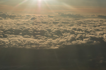 Panoramic view from the window of the plane flying above the sun-drenched clouds.
