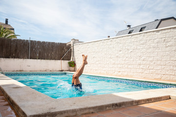 Young fitness man jumping into the water in the pool one day of summer vacation