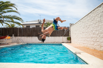 Young fitness man jumping into the water in the pool one day of summer vacation