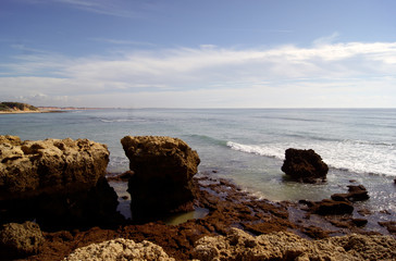 Fototapeta na wymiar Portugal, Albuferia. Late afternoon on the beach. Waves crash against the rocks.