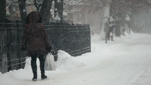 Urban people in the heavy snowstorm element and blizzard snowfall on the snowy street in the winter city 
