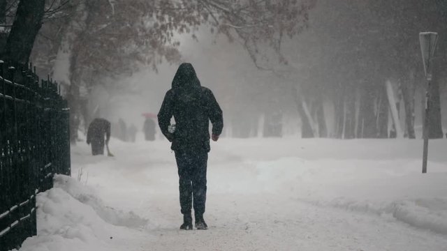 Urban people in the heavy snowstorm element and blizzard snowfall on the snowy street in the winter city 