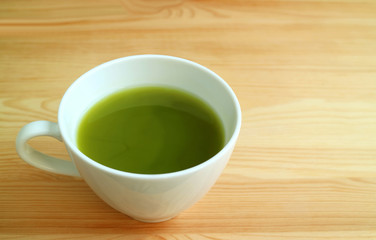 Vibrant Green Color Closeup a Cup of Hot Matcha Green Tea Isolated on Natural Brown Wooden Table