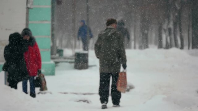 Urban people in the heavy snowstorm element and blizzard snowfall on the snowy street in the winter city 