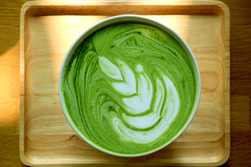 Obraz premium Top View of a Cup of Hot Matcha Green Tea Latte on Natural Wooden Tray 