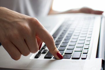 girl's hand typing on a laptop keyboard, she presses Enter key, moment of confirmation, close-up