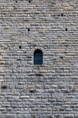 Fototapeta na wymiar muro di torre medievale con piccola finestra ad arco