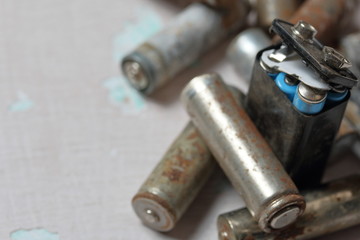 Spent batteries lie on the surface with peeling paint. Covered with corrosion. Recycling and environmental protection.