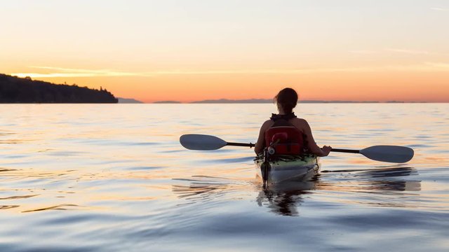 Cinemagraph of a Woman on a sea kayak is paddling in the ocean during a colorful and vibrant sunset. Taken in Jericho, Vancouver, British Columbia, Canada. Still Image Continuous Animation