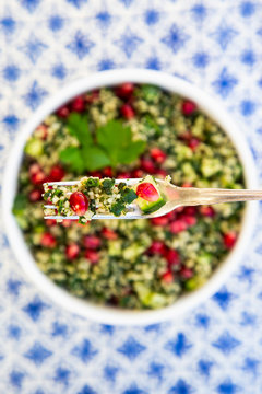 Overhead view of tabbouleh with pomegranate seeds on fork