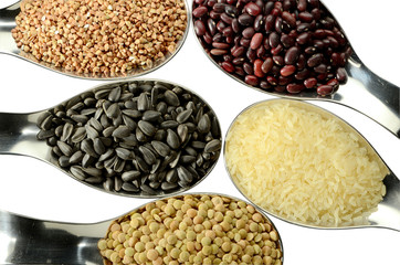 Rice, buckwheat, seeds, lentils, beans in spoons on an isolated surface.