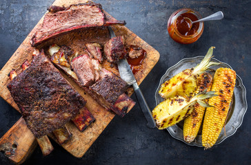 Barbecue sliced chuck beef ribs with hot rub with pineapple and corn as top view sliced on a wooden...
