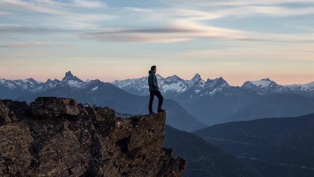 Adventurous man is standing on top of the mountain and enjoying the beautiful view during a vibrant sunset. Taken on top of Cheam Peak in Chilliwack, East of Vancouver, BC, Canada. Animation