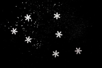 Abstract black background with isolated defocused snowflakes.