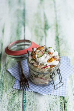 Glass of fried potato salad with cucumber, red radish, spring onions and mayonnaise yoghurt dressing