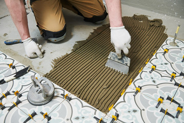 Tiler installing tile on bathroom floor. home indoors renovation
