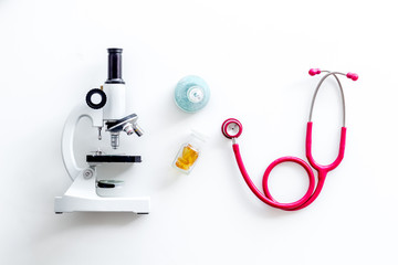 Medical tests on work table of doctor with microscope, stethoscope, test tube, pills on white background top view