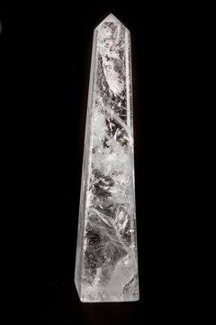 Beautiful cut white quartz obelisk stone on dark surface.