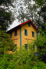 an old yellow two-storey cottage among the trees at the dacha