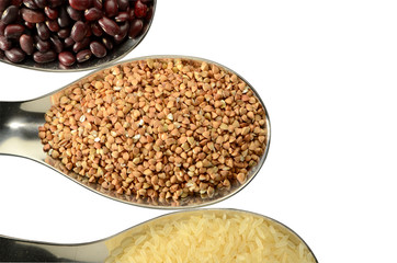 Beans, buckwheat, rice in spoons on an isolated background.
