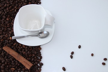 Cup and spoon with coffee grains in white background