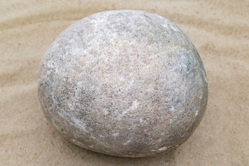 Fototapeta na wymiar Round stone lying on the sand