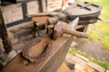 Tools in an old blacksmith's workshop. Horseshoe and hammer on a large anvil.