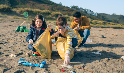 Group of young volunteers picking up trash on the beach