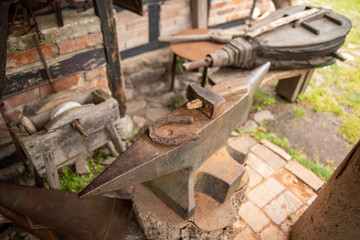 Tools in an old blacksmith's workshop. Horseshoe and hammer on a large anvil.