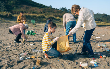 Grandmother and grandson with group of volunteers picking up trash on the beach