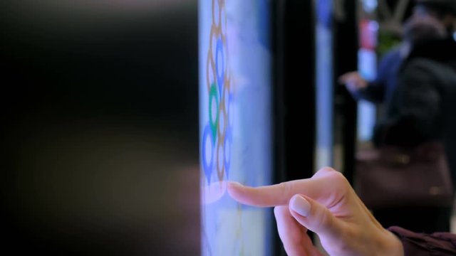 Woman hand using touchscreen display of electronic kiosk with interactive city map at street - scrolling and touching. Navigation, journey and technology concept