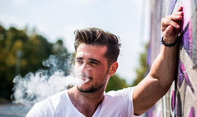 Handsome man smoking e-cigarette, vaping outdoor in city setting © theartofphoto