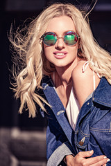 Beautiful smiling young woman looking happy in fashion style sunglasses on city center outdoor summer background. Closeup