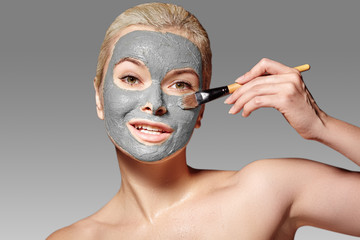 Beautiful Woman Applying Clay Facial Mask. Beauty Treatments. Spa Girl Apply Clay Facial mask with Beauty Brush