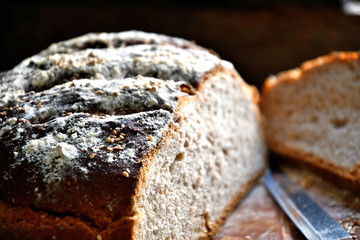 A loaf of bread with sesame cut on a cutting board.