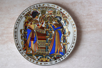 Egyptian antiquarian porcelain plate is made in national style. Egyptians in colourful national clothes are drawn on a plate.