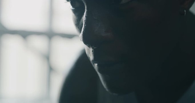 Cinematic slow motion close up shot of a professional young sweaty african man is after practicing shadow boxing work out in a ring. 