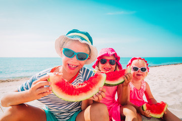 happy cute kids eating watermelon at beach