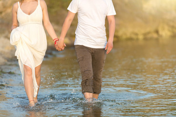 Couple holding hands walking romantic on beach on vacation travel holidays. Closeup of body and golden sand for copy space. Young loving couple