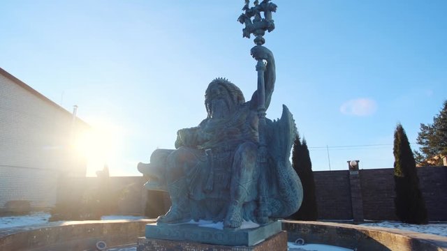 Statue of Neptune in fountain holding a trident in left hand and seashell in other one against blue sky in winter sunny day. Stock footage. Picturesque view of ancient God
