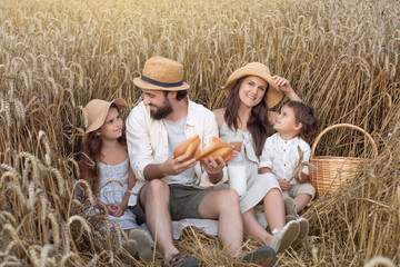 Naklejka na ściany i meble Happy family, father, mom, son and girl in straw hat in wheat field at sunset. The concept of organic farming and healthy lifestyle, healthy food, happiness and joy