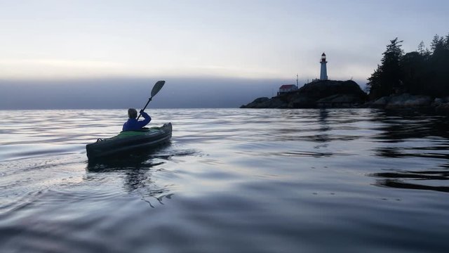 Adventure girl is kayaking on an inflatable kayak in Horseshoe Bay near Lighthouse Park. Taken in Vancouver, BC, Canada, during a winter sunset. Still Image Continuous Animation