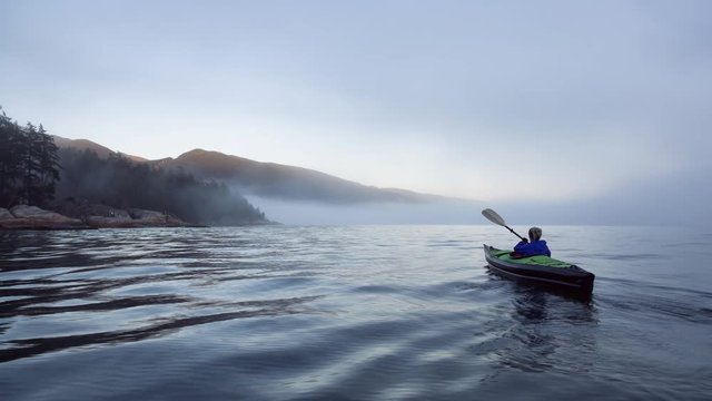 Adventure girl is kayaking on an inflatable kayak in Horseshoe Bay near Lighthouse Park. Taken in Vancouver, BC, Canada, during a winter sunset. Still Image Continuous Animation