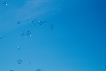  delicate fragile soap bubbles flying against the background of a blue cloudless sky on a summer day,