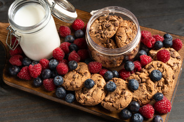 Lots of forest fruits and biscuits on wooden board, closeup shot.